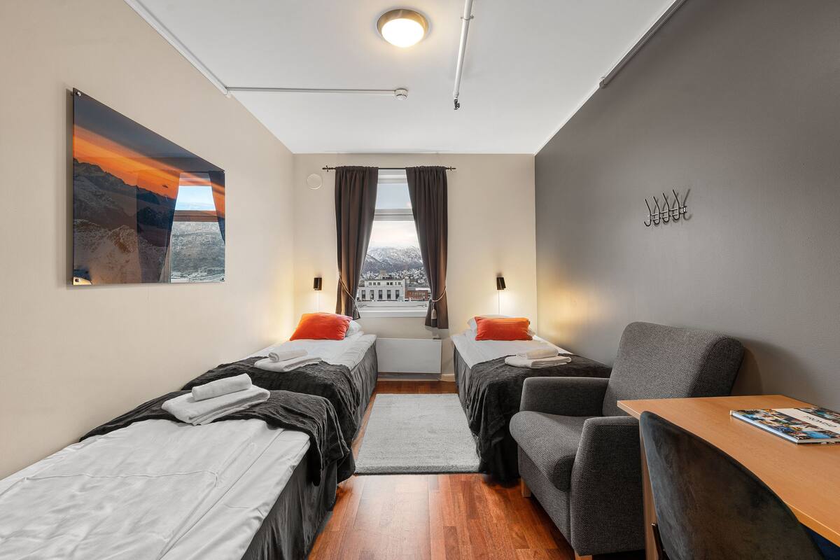 Una habitación de hotel moderna con dos camas individuales, un escritorio y una silla.