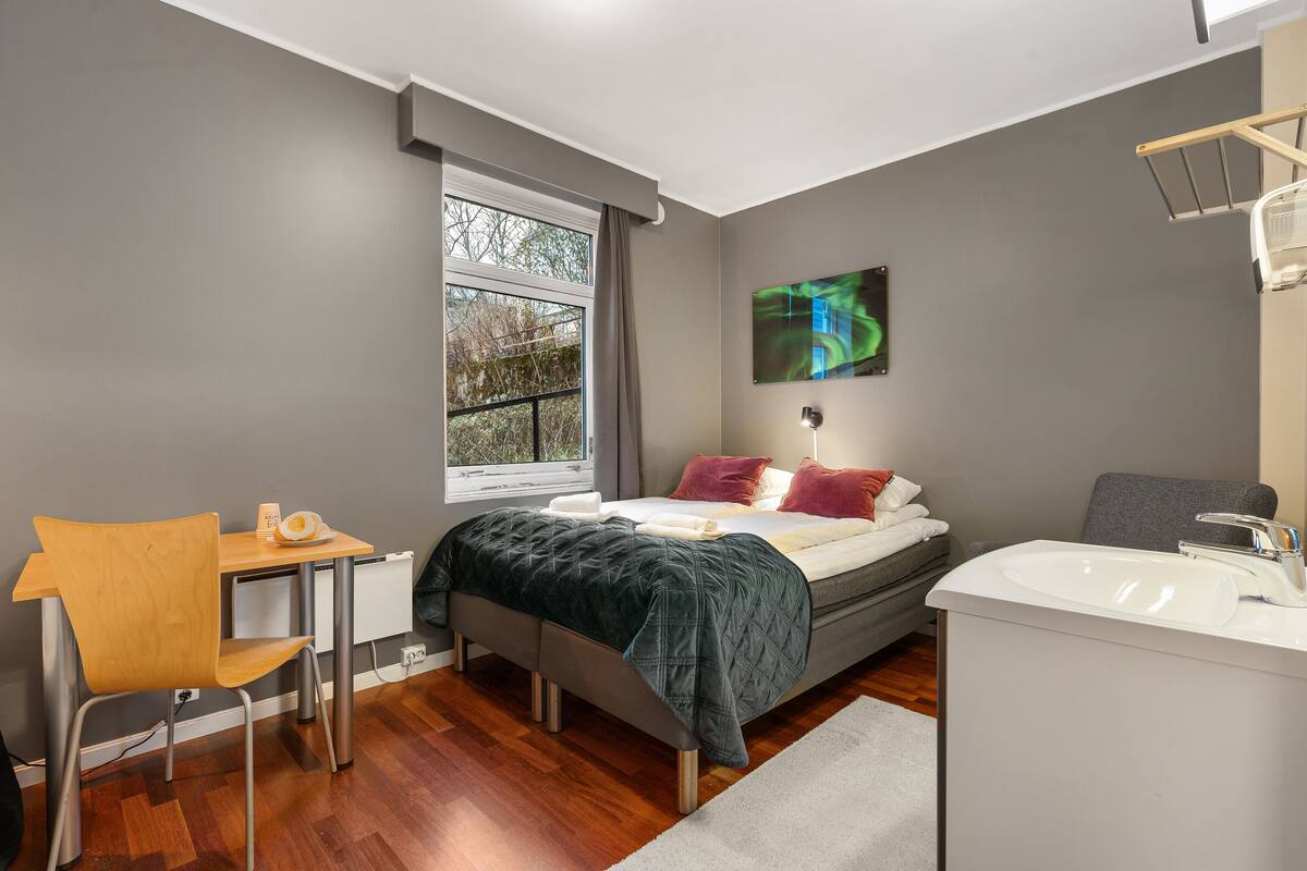 Un dormitorio moderno con cama, mesita de noche, silla y ventana.