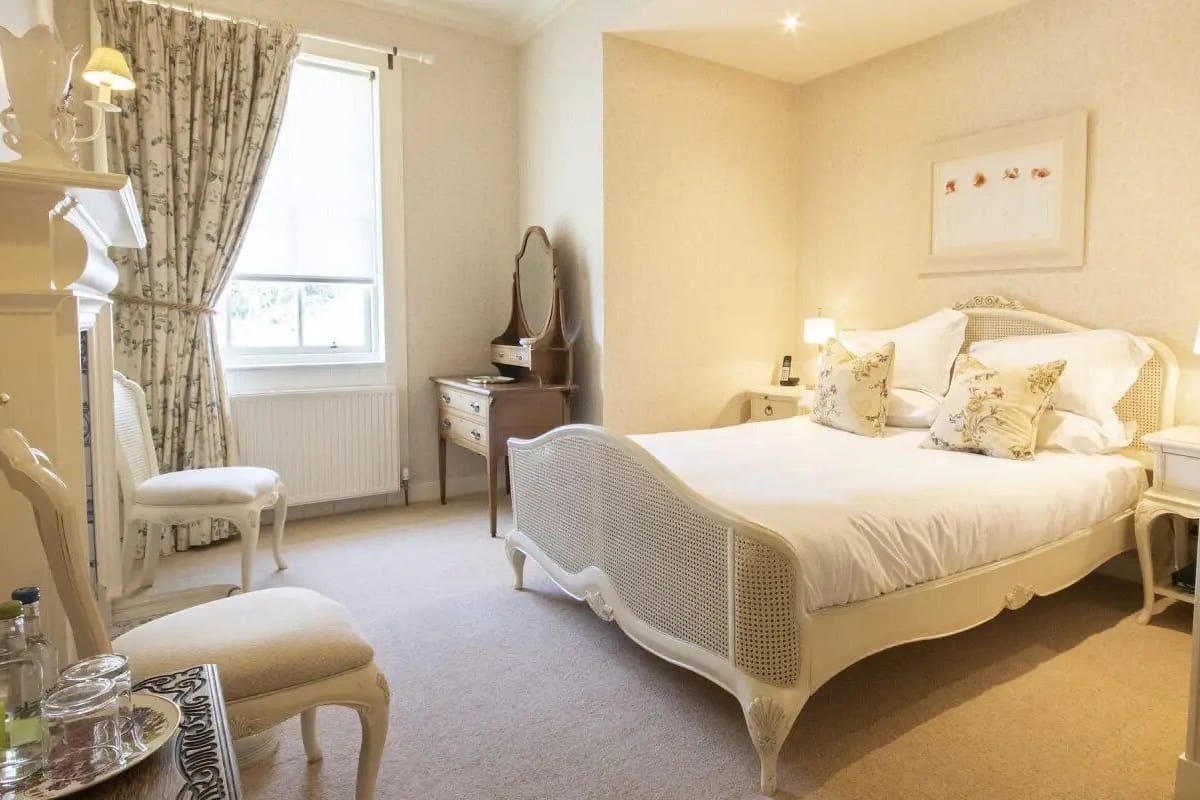 A bedroom with a large bed, a dresser, a chair, and a desk.