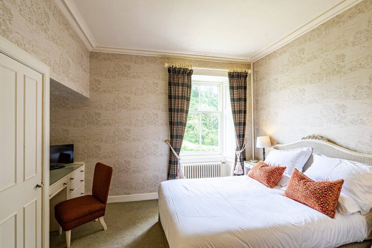 A bedroom with a bed, a desk, and a chair.