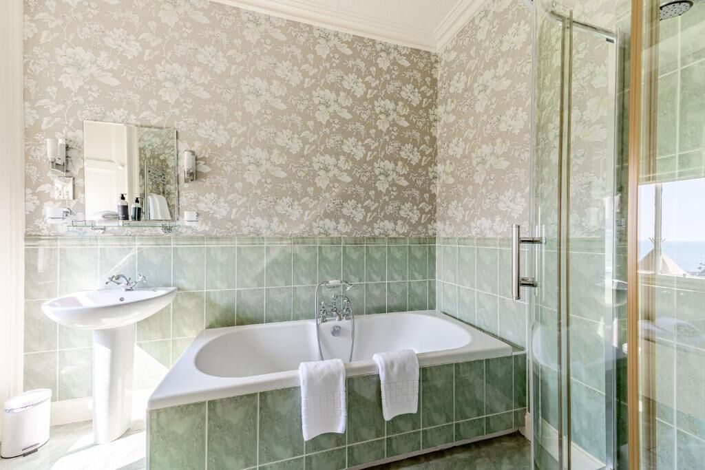Un baño con una bañera independiente, un lavabo pedestal y una ducha con mampara de vidrio.