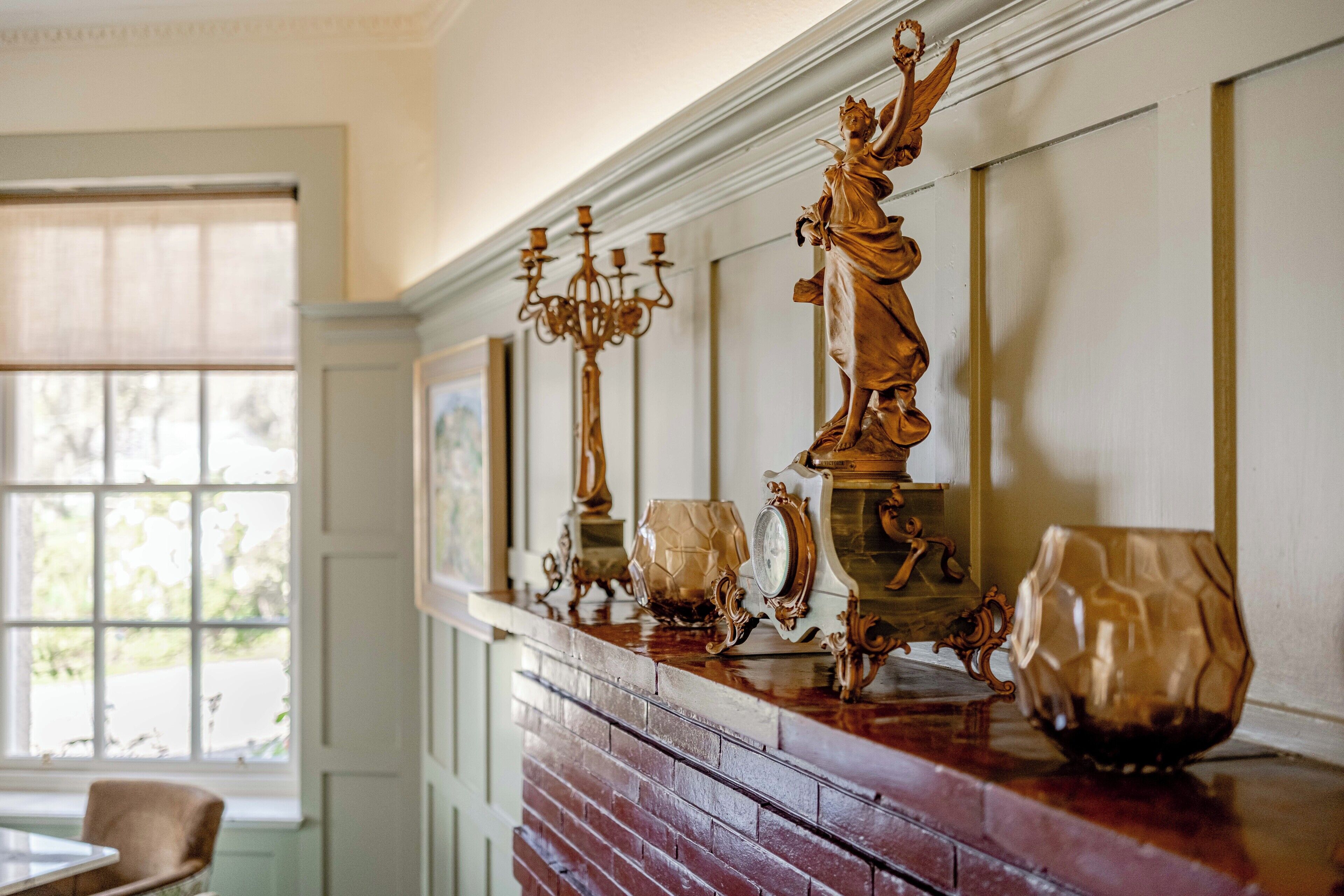 A fireplace with ornate decorations and a window in the background.