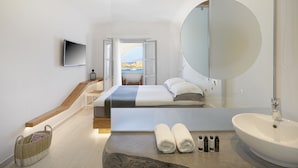 Een moderne hotelkamer met een bed, een grote spiegel, een bankje met een steenstructuur, een wastafel en uitzicht op de omgeving.