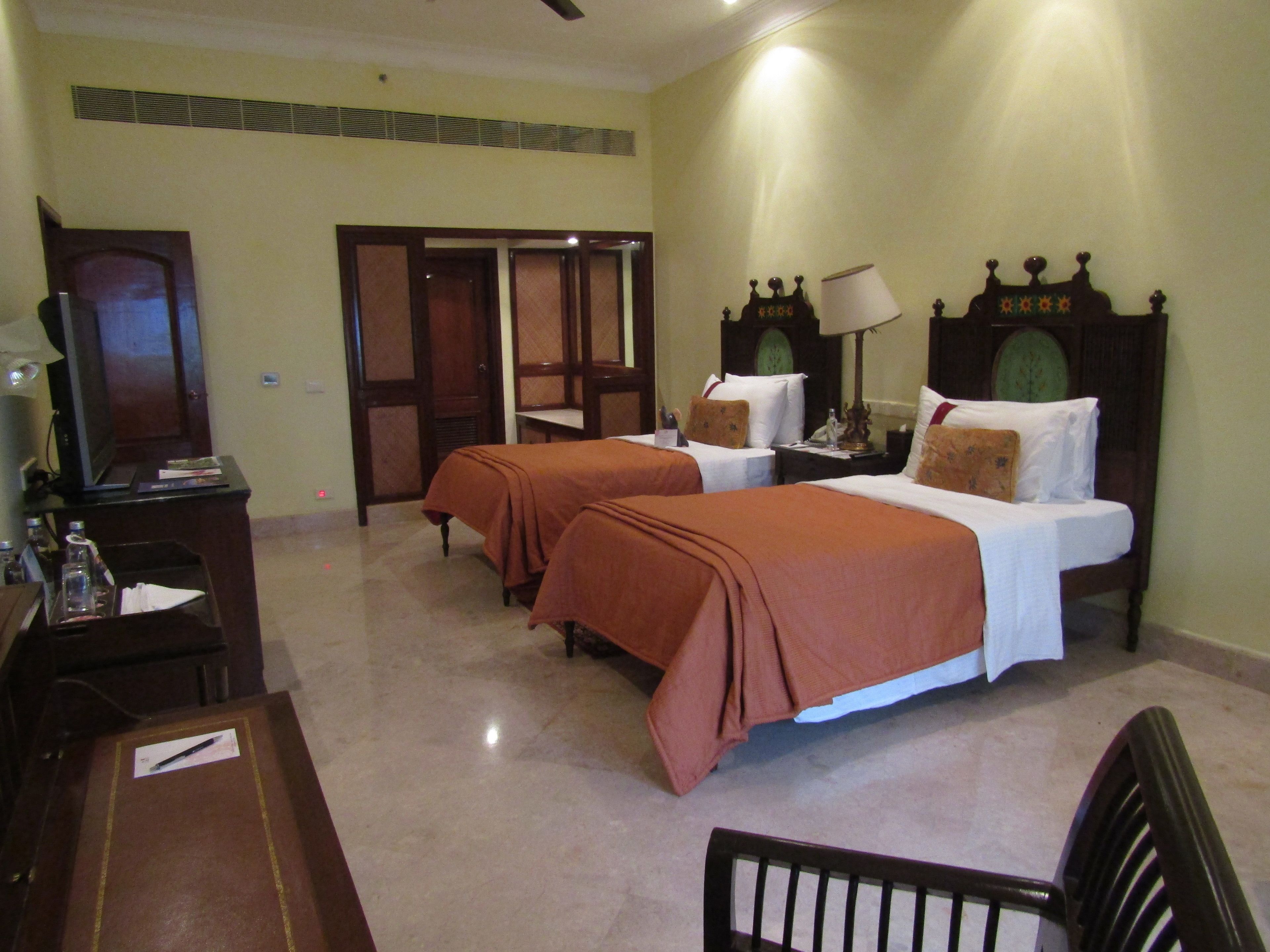 A hotel room with two beds, a desk with a television, and a chair.