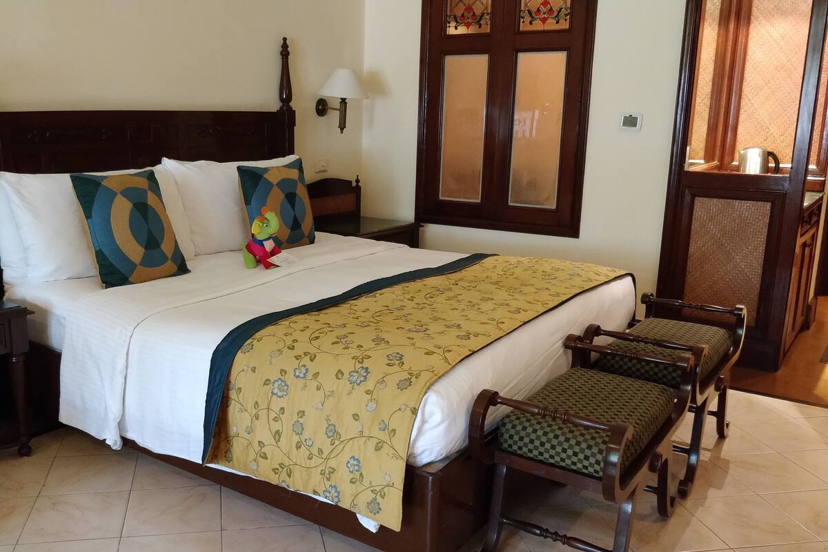 A neatly made bed with a floral bedspread, a telephone on the nightstand, and a small dinosaur toy on the bed.