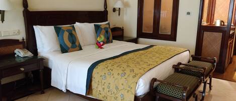 A neatly made bed with a floral bedspread, a telephone on the nightstand, and a small dinosaur toy on the bed.
