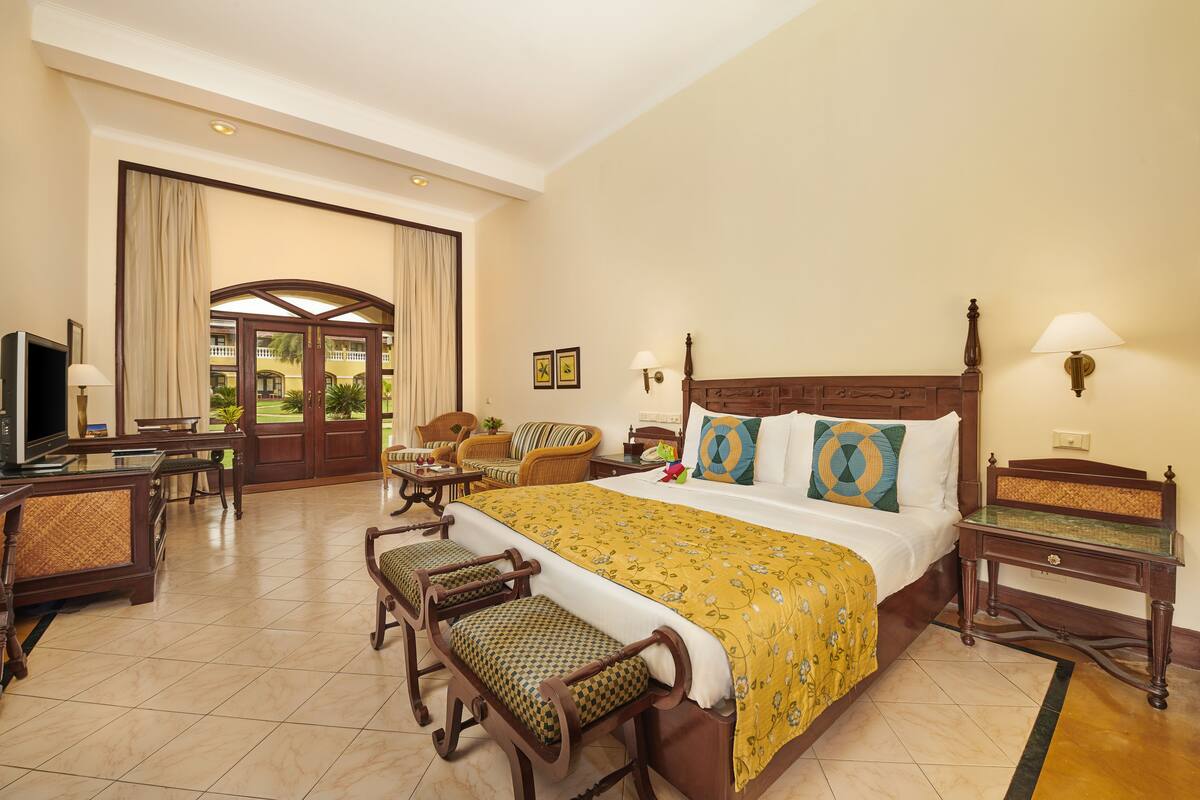 A hotel room with a large bed, a TV, a desk, and a seating area with chairs.