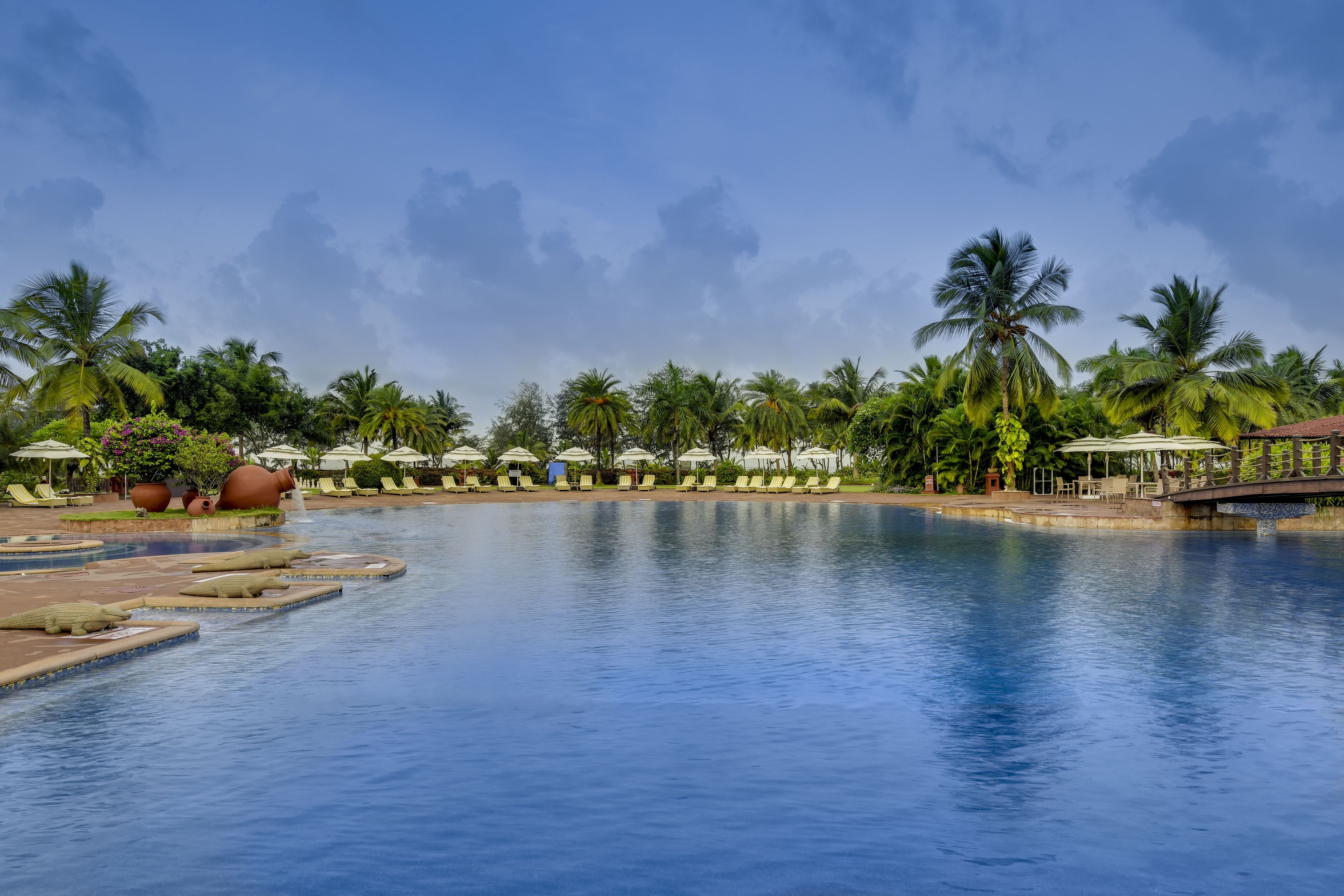 Ein großer Pool mit Liegestühlen und Palmen im Hintergrund.