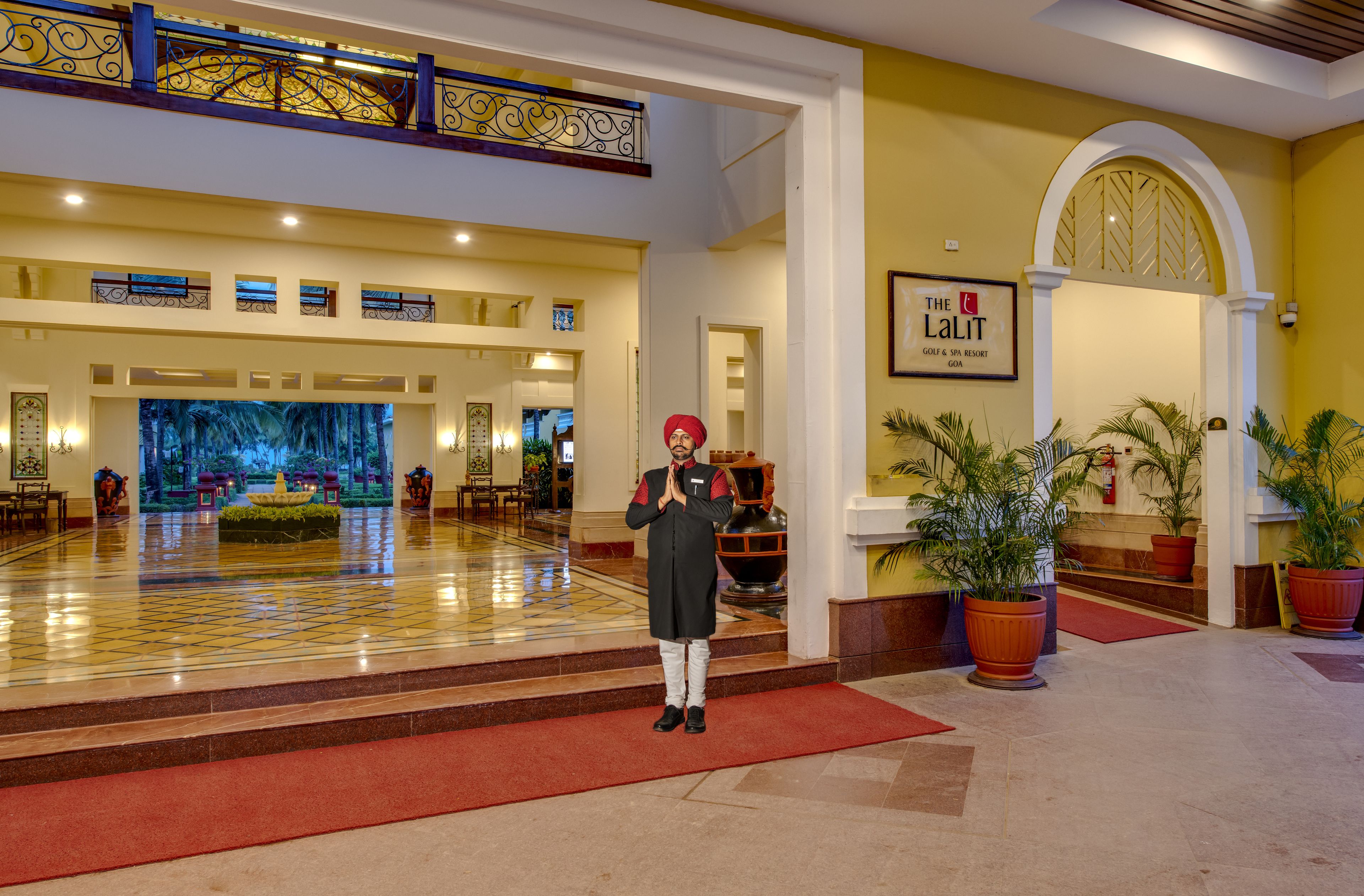 Un vestíbulo de hotel con suelo a cuadros, una fuente grande y un cartel que dice 'The LaLit'.