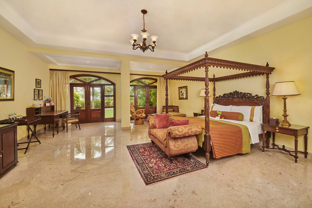 A spacious bedroom with a four-poster bed, a desk, and a chair.