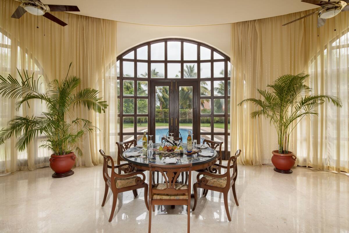 A dining area with a round table, chairs, and potted plants.