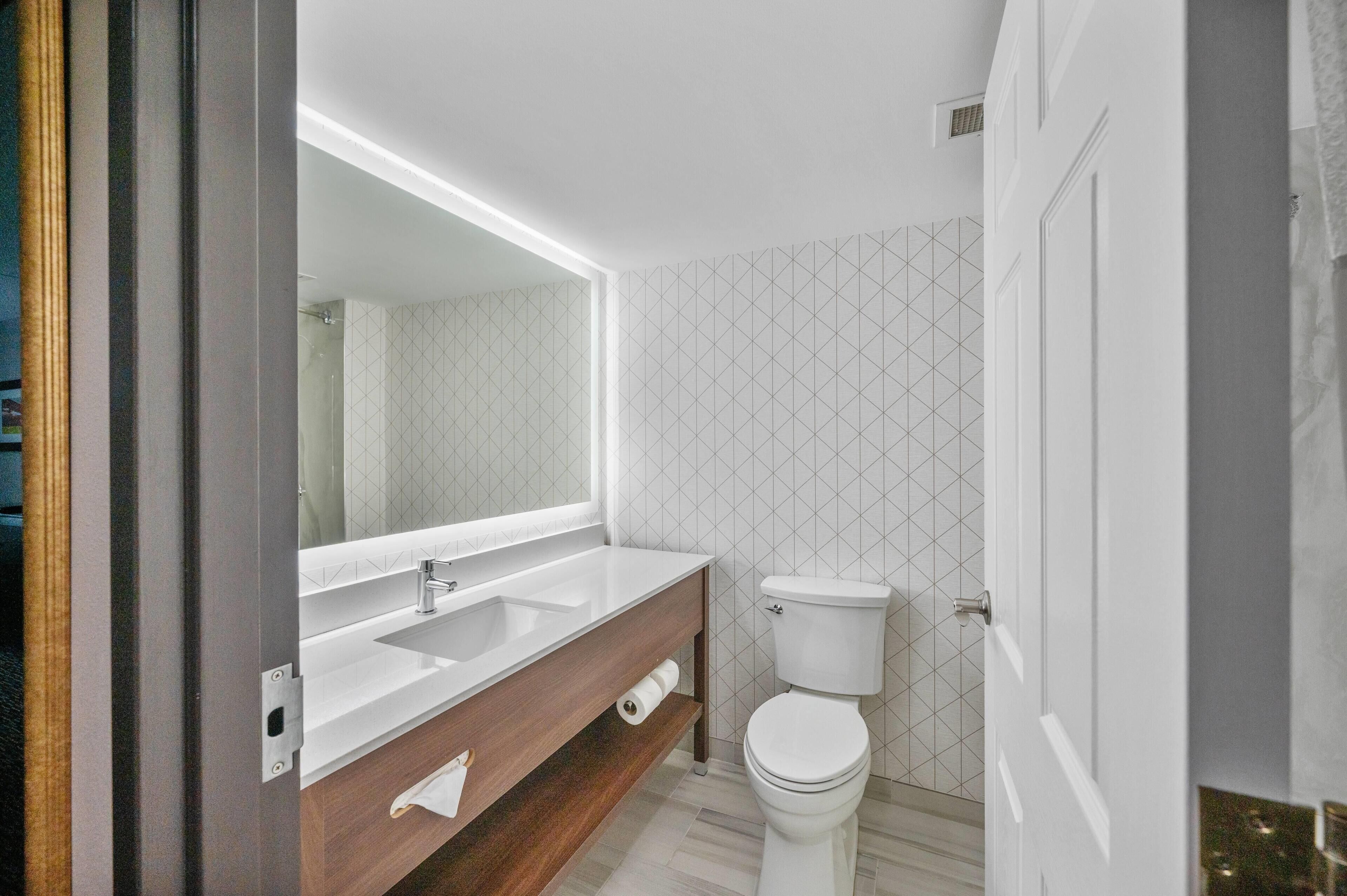 Ein modernes Badezimmer mit einem Waschbecken-Doppelwaschplatz, einer Toilette und einem großen Spiegel.