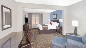 A hotel room with a bed, a desk, a chair, a television, and a lamp.