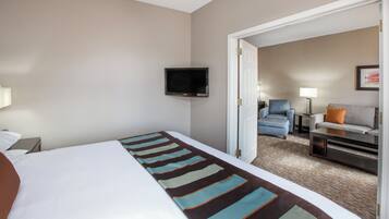 A hotel room with a bed, a television mounted on the wall, a sofa, and a chair.