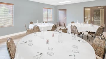 A conference room with multiple round tables, each set with chairs, water bottles, and name cards.
