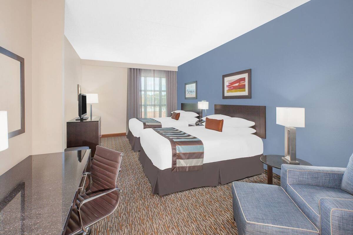 A hotel room with a large bed, two bedside tables, a desk, a chair, and a sofa.