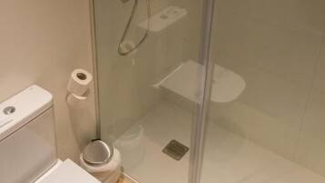 Box doccia in vetro con servizi igienici e un rotolo di carta igienica.