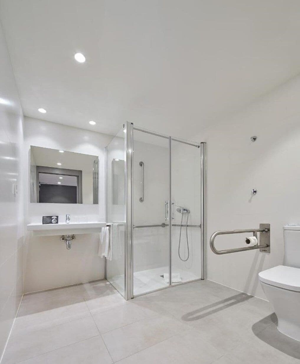 Un baño moderno con ducha envuelta en vidrio, un lavabo blanco y un inodoro.