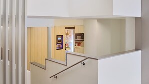 Een modern interieur met een trap die naar een lager gelegen niveau leidt, een geïntegreerde keuken en een automaat.