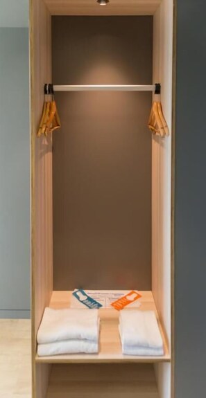 A wooden closet with a hanging rod and a shelf with folded towels. - Hostal Lami (Esplugues de Llobregat)