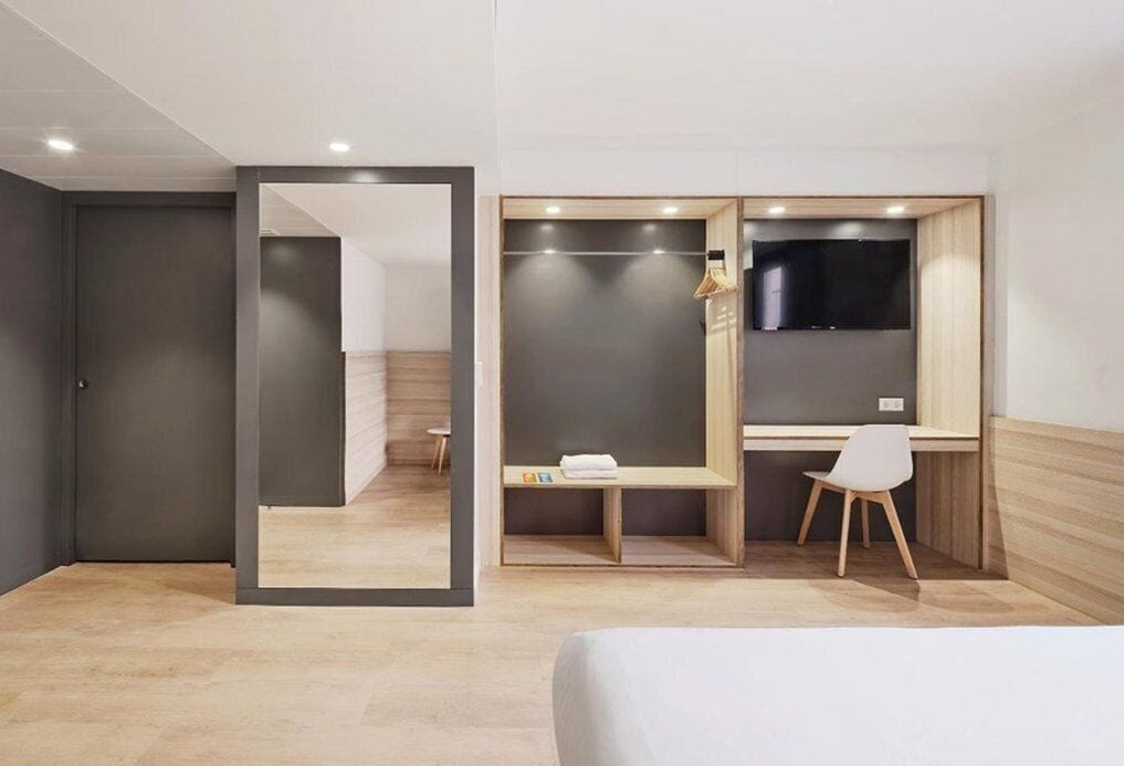Een moderne hotelkamer met een bed, een bureau en een televisie.