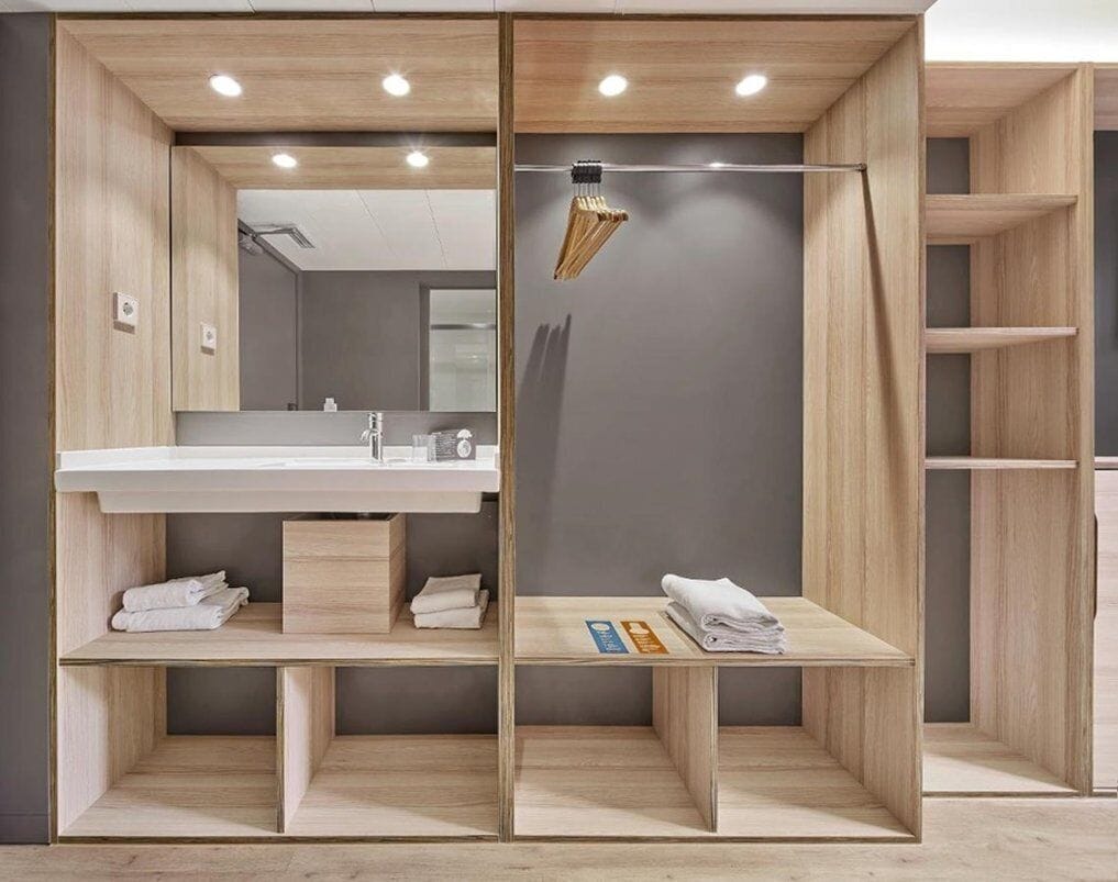 A modern bathroom with a wooden vanity, a mirror, and a towel rack.