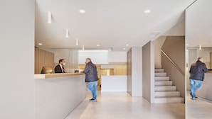 Een moderne hotel lobby met een receptiebalie, een trap en een minimalistisch design.