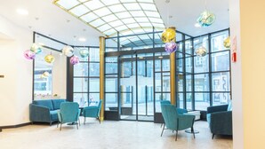 A spacious lobby with a glass door entrance, teal seating, and hanging disco balls. - Pilvax Hotel Budapest (Budapest)