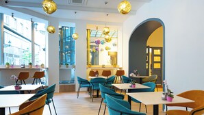 A modern interior with tables and chairs, a large window, and a mirror. - Pilvax Hotel Budapest (Budapest)