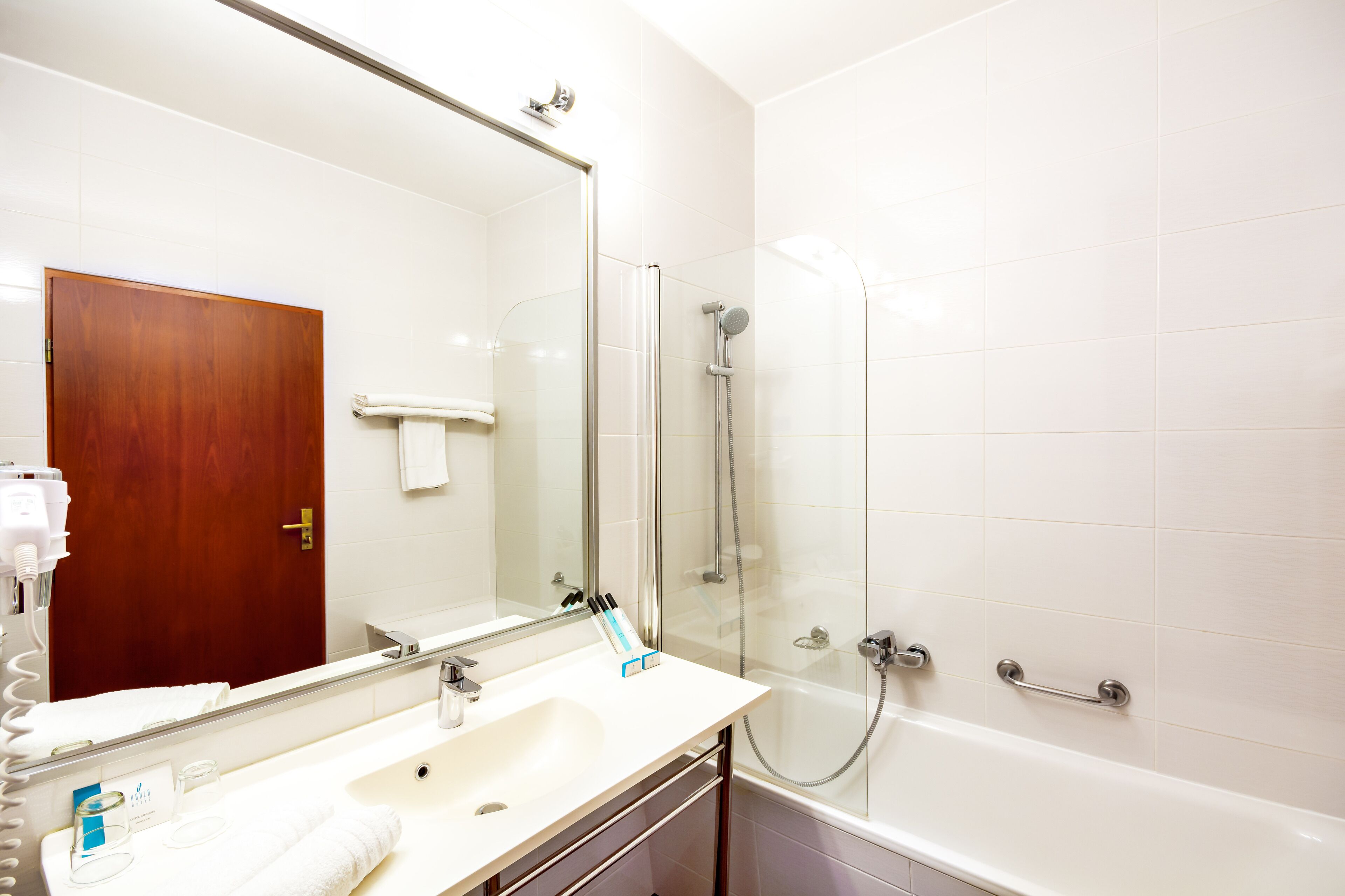 A bathroom with a sink, mirror, and shower.