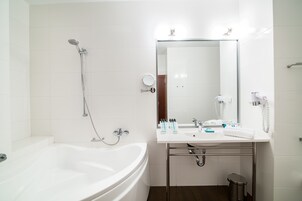 A modern bathroom with a white bathtub, a sink with a mirror, and a shower.