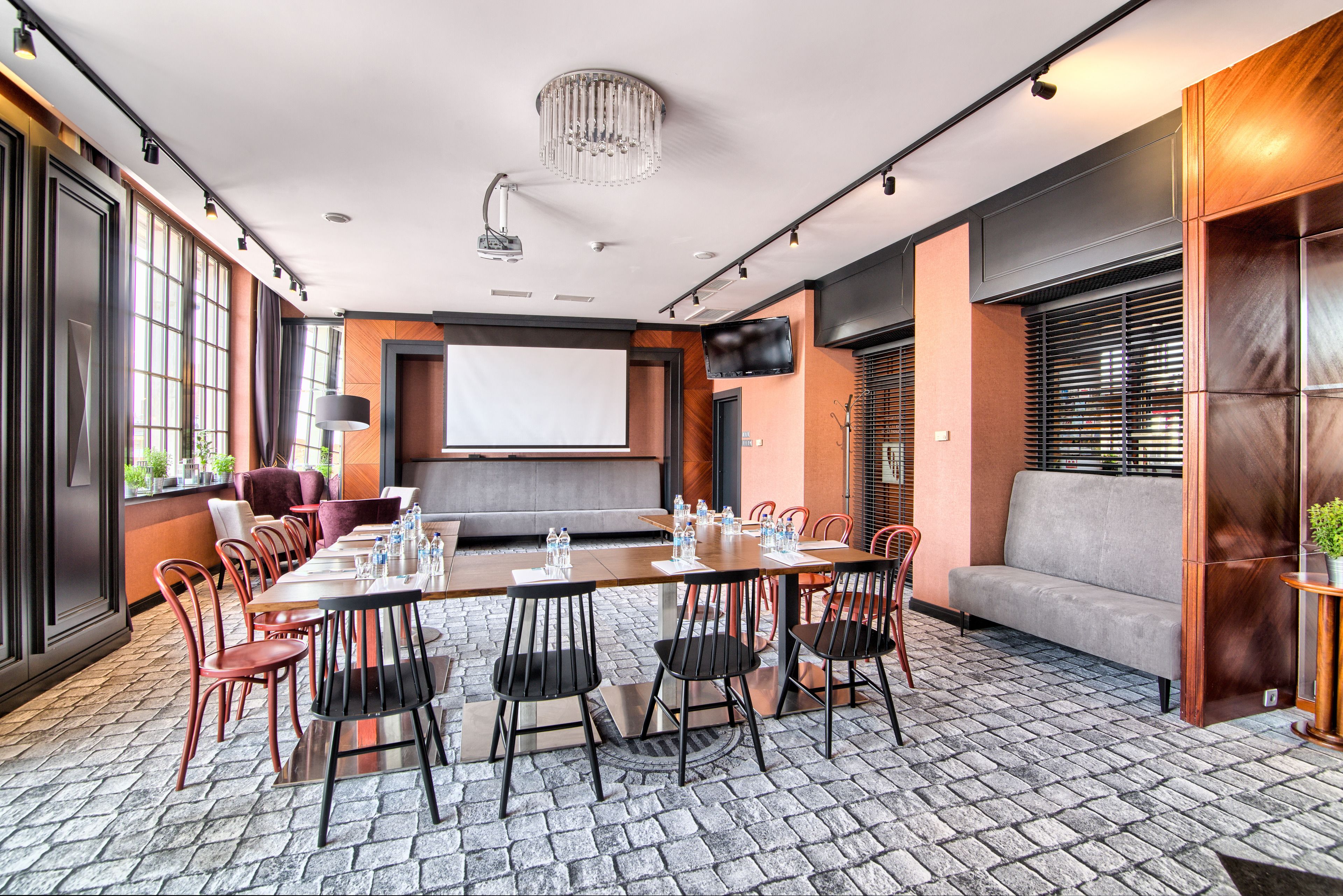 A conference room with a long table, chairs, a sofa, and a TV screen.