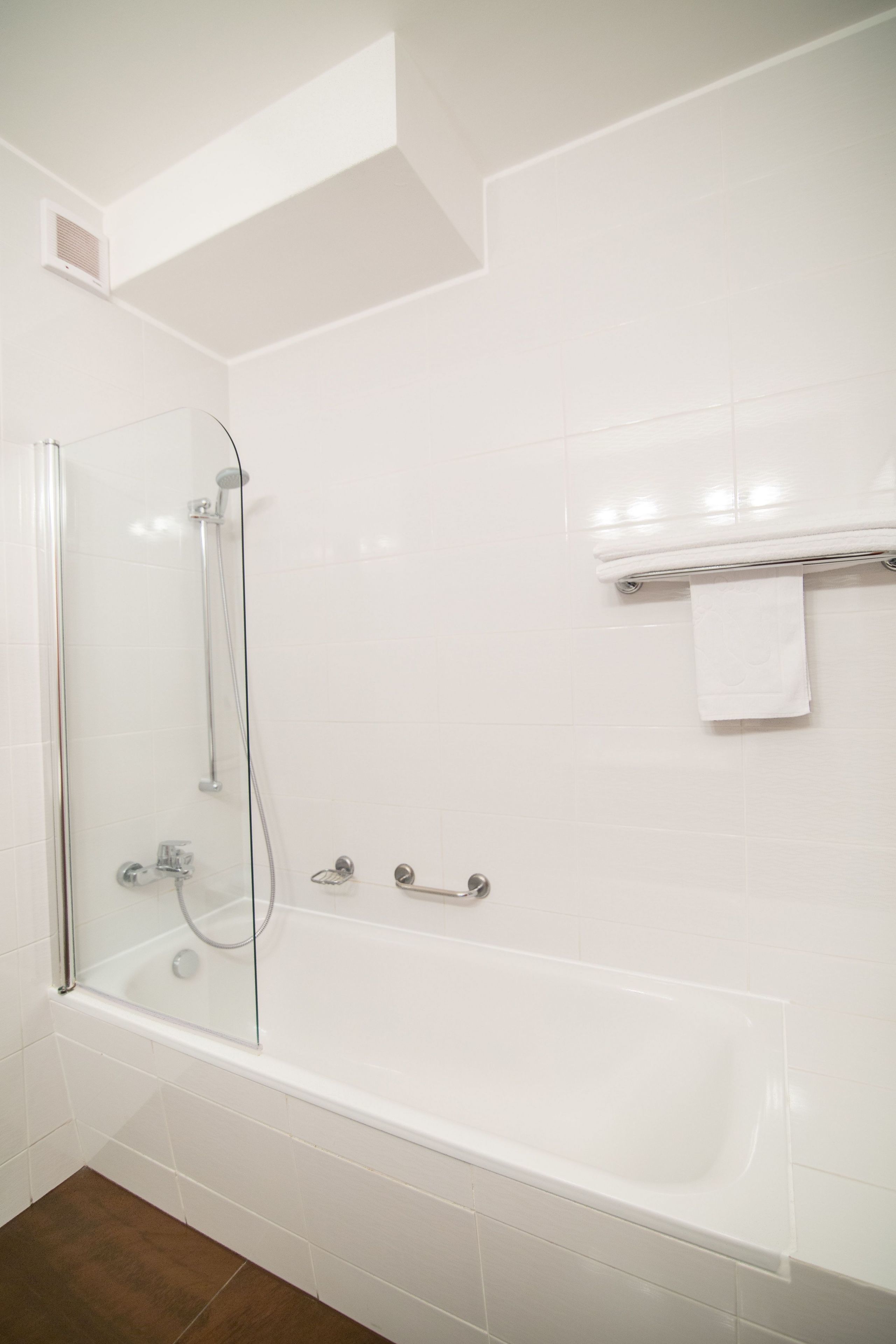 Une salle de bain moderne avec une douche à parois de verre, une baignoire blanche et un porte-serviettes.