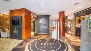 A hotel lobby with a central circular emblem, a television mounted on a wooden panel, and a large framed picture of a building.