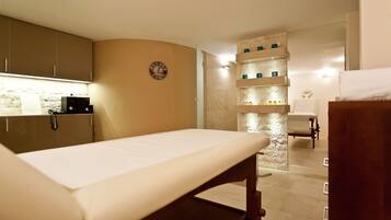 A clinical examination room with a bed, a sink, and a counter with cabinets.