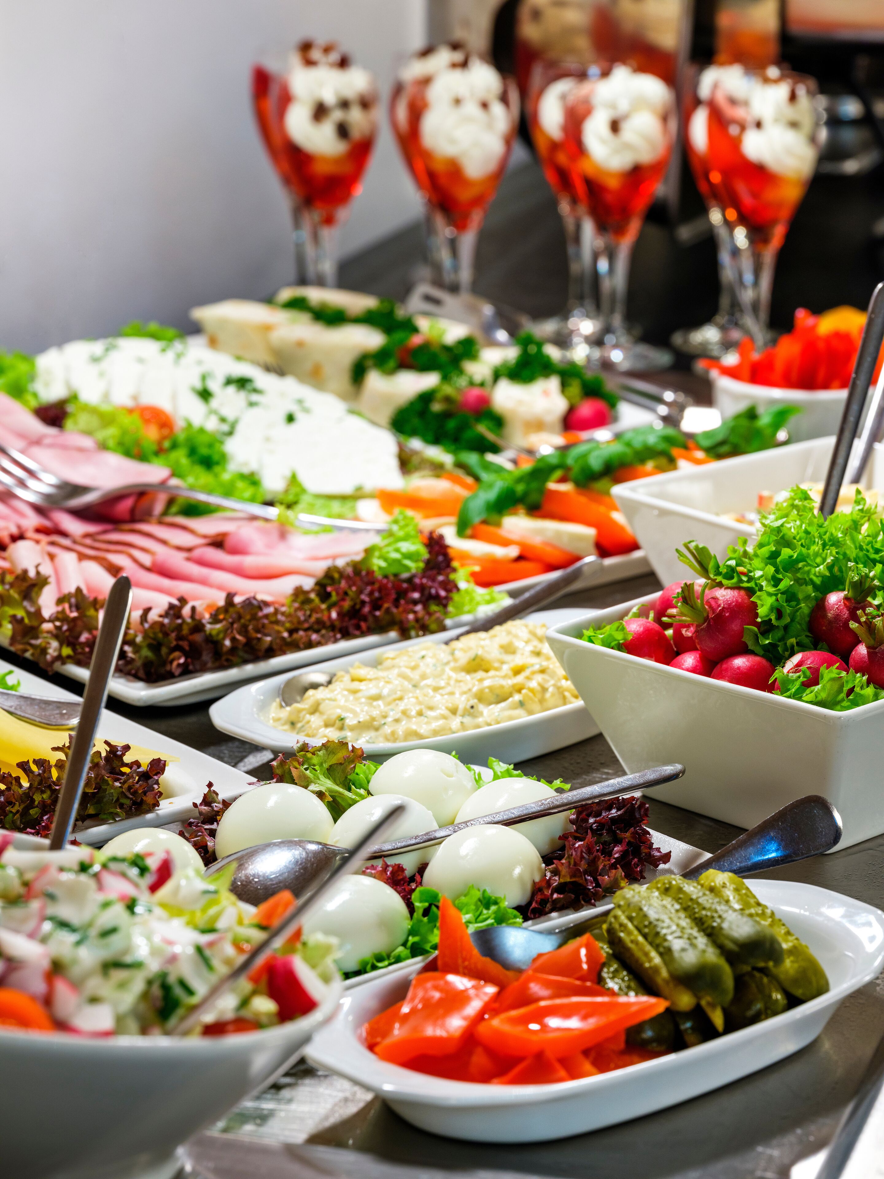 A buffet with various dishes including salads, meats, and desserts.