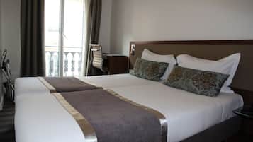 A hotel room with two beds, a balcony, and a chair.