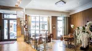 A hotel lobby with a reception desk, seating area, and large windows. - Art Hotel (Paris)
