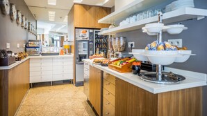 A modern kitchen area with a coffee station, a refrigerator, and a buffet setup. - Art Hotel (Paris)