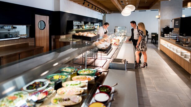 A buffet with various food options, a bar area with bottles, and a counter where staff are serving.