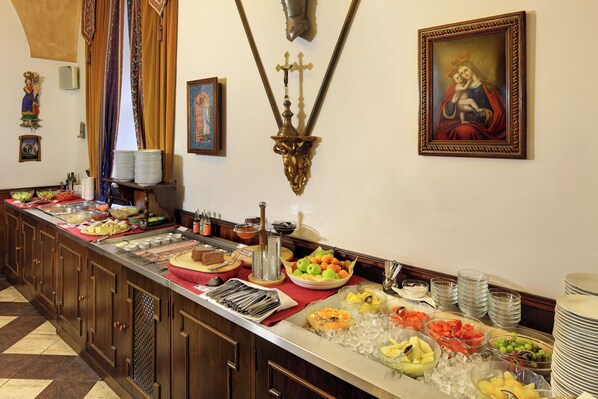 A buffet with various food items and a religious painting on the wall.