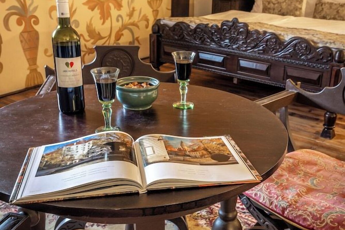 Una habitación con una mesa redonda, un libro, una botella de vino y copas.
