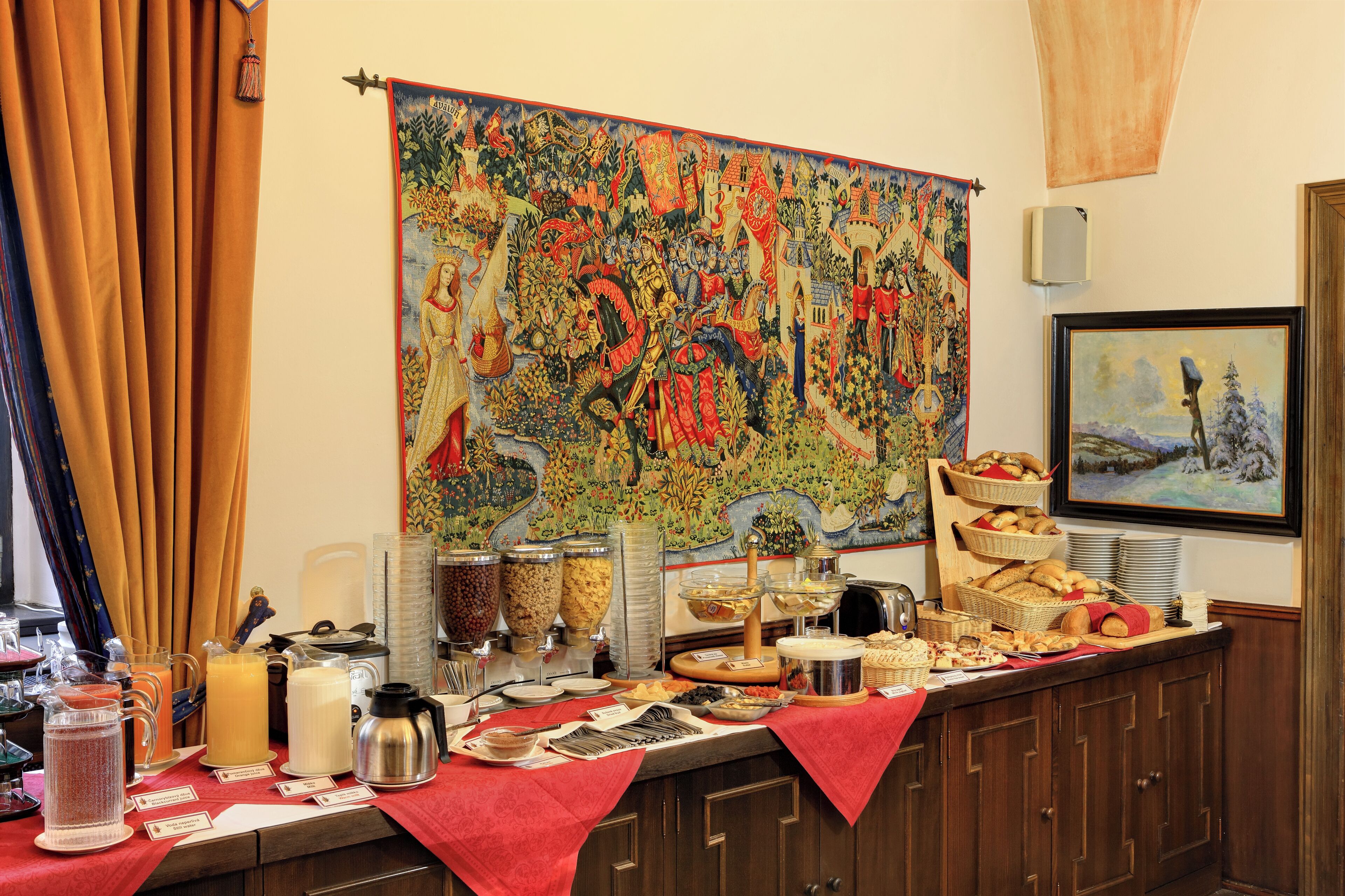 Mesa de buffet con diferentes alimentos y un tapiz grande en la pared.