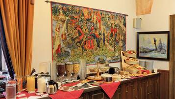 Mesa de buffet con diferentes alimentos y un tapiz grande en la pared.