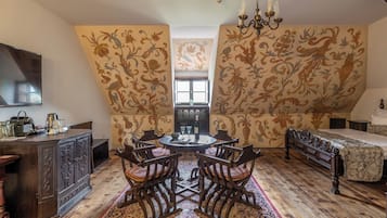 A room with a round table, four chairs, a bed, and a dresser.