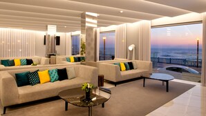 A modern living room with a sofa set, a coffee table, and a view of the ocean.
