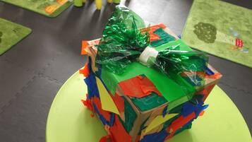 Un regalo colorido envuelto en papel verde, rojo y azul, sobre una superficie verde.