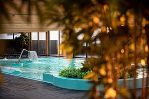 Una piscina techada, sombrillas, sillones reclinables de piscina