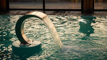 A water feature with a curved spout in a pool area.
