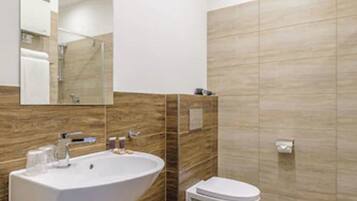Un baño moderno con un lavamanos grande, inodoro y espejo.